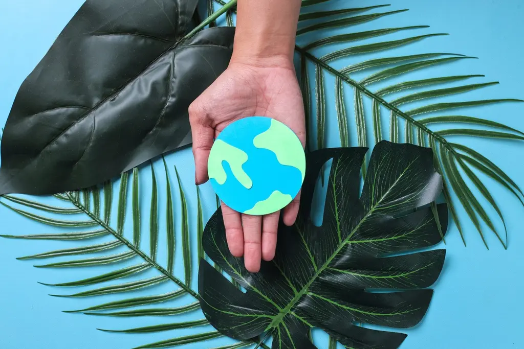 Hand holding a small earth among green leaves, representing eco-friendly cleaning in Maidstone