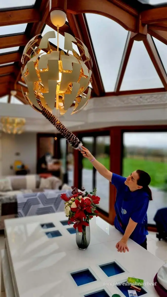 Cleaning With Meaning cleaner dusting a light fitting in a Kent home